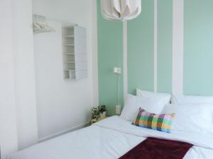 a bed with white sheets and a colorful pillow at Strasbourg Evasion Pop in Strasbourg