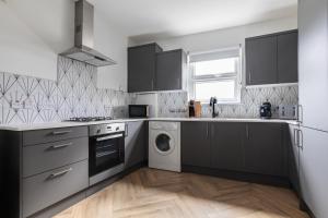 uma cozinha com armários pretos e uma máquina de lavar e secar roupa em Beautiful 3BR Flat with Desks and Fast Wi-Fi em Londres