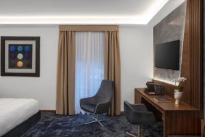 Habitación de hotel con cama, escritorio y TV. en Hotel Via Veneto en Roma