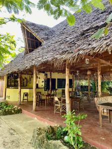 Embe Lodge في كيزيماكزي: مطعم بسقف من القش وبه طاولات وكراسي