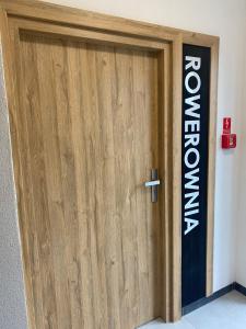 a wooden door with a sign on a wall at River Song Apartment in Nowe Miasto Lubawskie