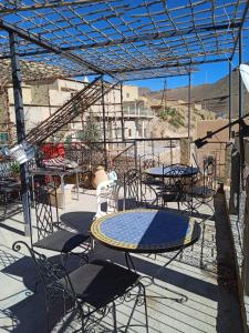 un patio con tavoli e sedie sotto una struttura metallica di Auberge amougar a Zemmour Touirza