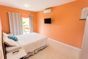 Panorama Cumbuco في كومبوكو: غرفة نوم بجدران برتقالية وسرير وتلفزيون