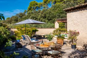 patio con tavolo, sedie e ombrellone di Domaine de Valloncourt a Cheval-Blanc