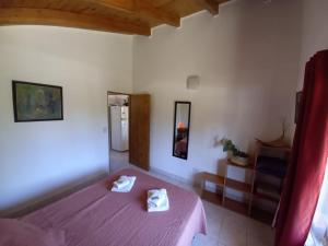 1 dormitorio con 1 cama morada y 2 toallas en Cabañas Mérida Ruta 66 en El Hoyo