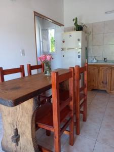a kitchen with a wooden table with chairs and a refrigerator at Cabañas Mérida Ruta 66 in El Hoyo