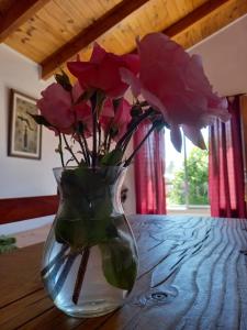 a vase filled with pink roses sitting on a table at Cabañas Mérida Ruta 66 in El Hoyo