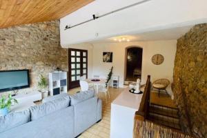 sala de estar con sofá grande y pared de piedra en Gîte des 3 vallées - Le soleil des Cévennes, en Saint-Jean-du-Gard