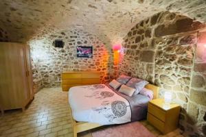 Un dormitorio con una cama en una pared de piedra. en Gîte des 3 vallées - Le soleil des Cévennes, en Saint-Jean-du-Gard