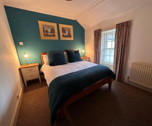 een slaapkamer met een bed met blauwe muren en een raam bij Spean Lodge in Spean Bridge