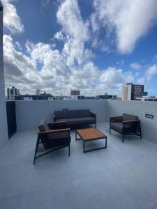 a patio with three chairs and a table on a roof at FLAT aconchegante e moderno, 100m do mar in Cabedelo