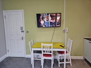 a dining room table with chairs and a tv on the wall at Spacious Studio in London in London