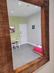 a mirror reflecting a bedroom with a red bed and a table at Spacious Studio in London in London