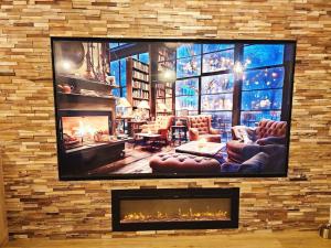 a living room with a tv on a brick wall at La Parenthèse - Votre Cocon au Centre d'Oyonnax in Oyonnax