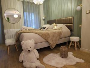 1 dormitorio con 1 cama con osito de peluche en el suelo en La Parenthèse - Votre Cocon au Centre d'Oyonnax, en Oyonnax