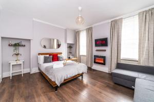 ein Schlafzimmer mit einem Bett, einem Sofa und einem Kamin in der Unterkunft [Covent Garden-Oxford street] Central London Studio Apartment in London