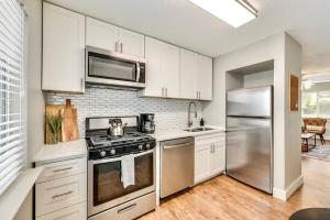 a kitchen with stainless steel appliances and white cabinets at Near Downtown Dallas - The Dapper Charm in Dallas