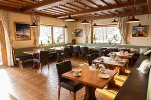 un ristorante con tavoli e sedie in legno e finestre di Pension Dachsteinhof a Ramsau am Dachstein