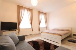 1 dormitorio blanco con 1 cama y TV en Apartmán Jabloňovka, en Karlovy Vary