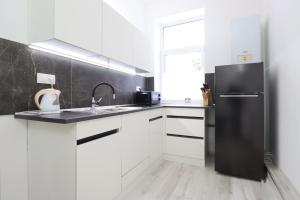 cocina con armarios blancos y nevera negra en Apartmán Jabloňovka, en Karlovy Vary