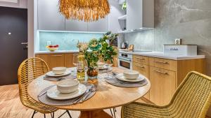 Rezydencja Niechorze 129 - 5D Apartamenty في نيخوجة: مطبخ مع طاولة خشبية مع كراسي وغرفة طعام