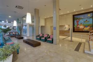 a lobby with chairs and a large painting on the wall at Hotel Porto Sol Ingleses in Florianópolis