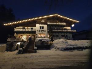 Un bâtiment avec des lumières dans la neige dans l'établissement Boutique Hotel Alpenhof, à Sankt Martin am Tennengebirge