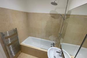 a bathroom with a shower and a sink and a tub at Spacious 1BD Flat - Next to Richmond Riverside! in Richmond