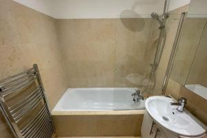 a bathroom with a bath tub and a sink at Spacious 1BD Flat - Next to Richmond Riverside! in Richmond