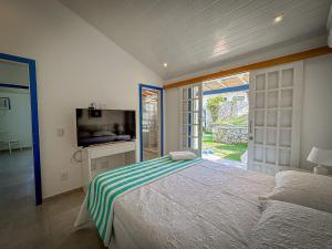 1 dormitorio con 1 cama y TV en BZ61 Casa com Piscina a 50m da Praia da Ferradura, en Búzios