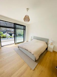 biała sypialnia z łóżkiem i dużym oknem w obiekcie Modern townhouse with Private Garden w mieście Differdange