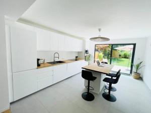 cocina con armarios blancos, mesa y sillas en Modern townhouse with Private Garden, en Differdange