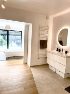 a white bathroom with a bed and a mirror at Modern townhouse with Private Garden in Differdange