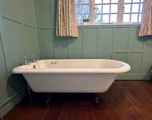bañera blanca en una habitación verde con ventana en Spean Lodge en Spean Bridge