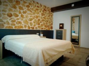 - une chambre avec un grand lit et un mur en pierre dans l'établissement Casona El Lavador de Tazona, à Tazona