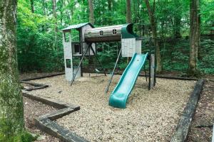 a playground with a slide in the woods at Tiny Home Cottage Near the Smokies #1 Olga in Sevierville