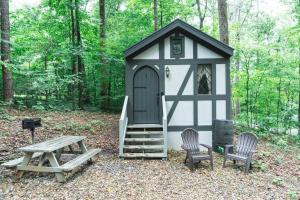 un capannone bianco e nero con due sedie e un tavolo da picnic di Tiny Home Cottage Near the Smokies #1 Olga a Sevierville