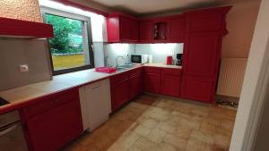 a kitchen with red cabinets and a window at Gîte Les Copains de Maui in Baerenthal
