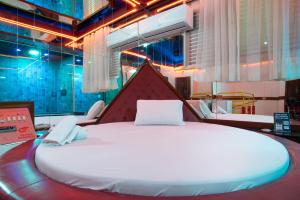 Motel Fantasy 5 في بيلو هوريزونتي: سرير أبيض كبير في غرفة بها أضواء