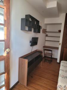 ein Wohnzimmer mit einem Schreibtisch und einem TV an der Wand in der Unterkunft My Home 2 quartos em Cobertura ao lado da praia in Rio de Janeiro