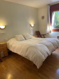 uma grande cama branca num quarto com uma janela em Chez Maurice avec une belle vue em El Tarter