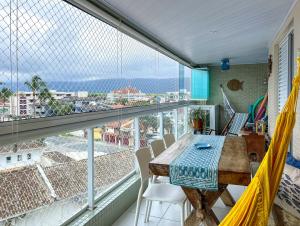a balcony with a table and chairs and a large window at Apto a 350m da Praia de Maitinga em Bertioga SP in Bertioga