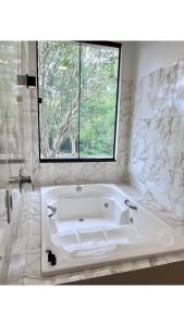 uma banheira branca na casa de banho com uma janela em Hotel Fazenda Vale Alvorada em Cascavel