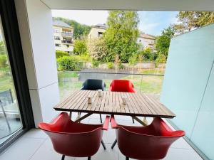 d'une table en bois et de chaises rouges sur un balcon. dans l'établissement Luxury Green Flat in Center with Parking & Terrace, à Luxembourg