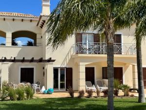 阿爾布費拉的住宿－Villa Cascata, 3 bedroom, Pool, close to Olhos de Agua，院子里有棕榈树和椅子的房子
