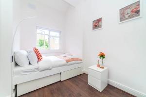 a white bedroom with a bed and a window at Radiant and Roomy 2BD Flat - Fulham! in London
