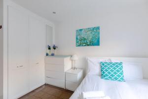 a bedroom with a white bed with a blue pillow at Radiant and Roomy 2BD Flat - Fulham! in London