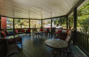 une véranda avec des tables, des chaises et un chercheur de table dans l'établissement Villa de Brome, à Lac-Brome