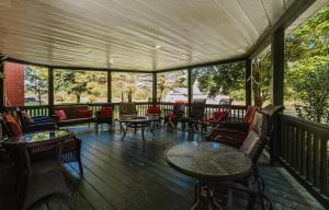 um alpendre coberto com mesas, cadeiras e mesa em Villa de Brome em Lac-Brome