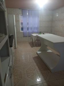 una cocina con encimera blanca y mesas. en Pousada Estrela Azul, en São Gabriel